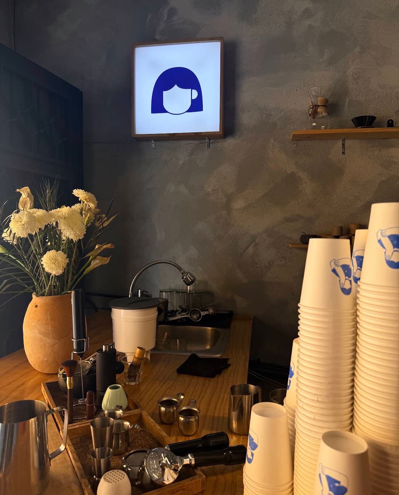 La barra de Mulier con el letrero de la casa, flores y vasos para llevar